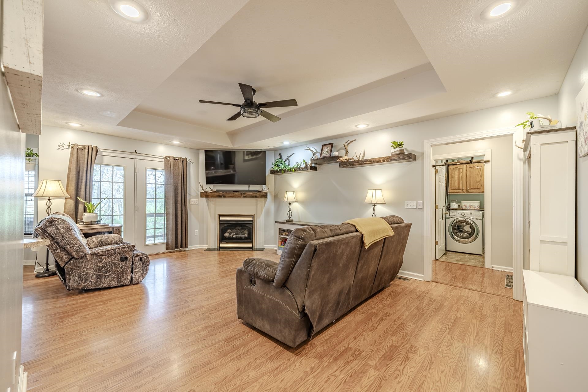 270 2 Boys Road Savannah, TN 38372 - Photo 5 of 35 Living room featuring a tray ceiling, washer / dryer, light wood-style flooring, a ceiling fan, and a fireplace