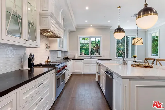 a large kitchen with kitchen island granite countertop a stove a sink a center island and wooden floor