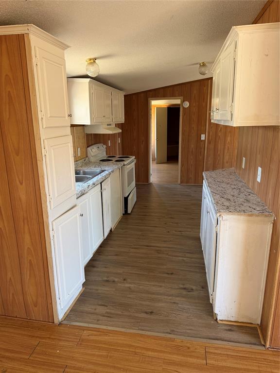 128 Rommel Court Springtown, TX 76082 - Photo 11 of 15 Kitchen featuring white cabinetry, wood-finish flooring, white appliances, and a vaulted ceiling