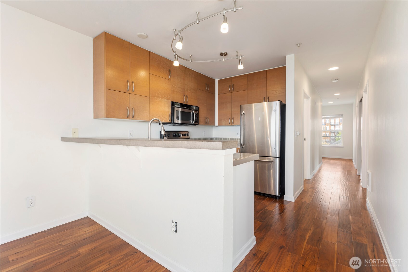 2440 Western Avenue, Unit 807 Seattle, WA 98121 - Photo 6 of 32 a kitchen with stainless steel appliances a refrigerator and wooden floor