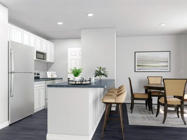 a kitchen with stainless steel appliances granite countertop a dining table chairs refrigerator and sink
