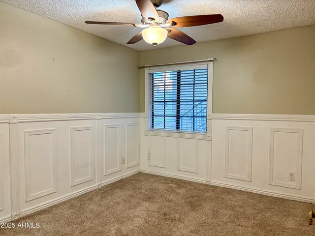 an empty room with windows and fan