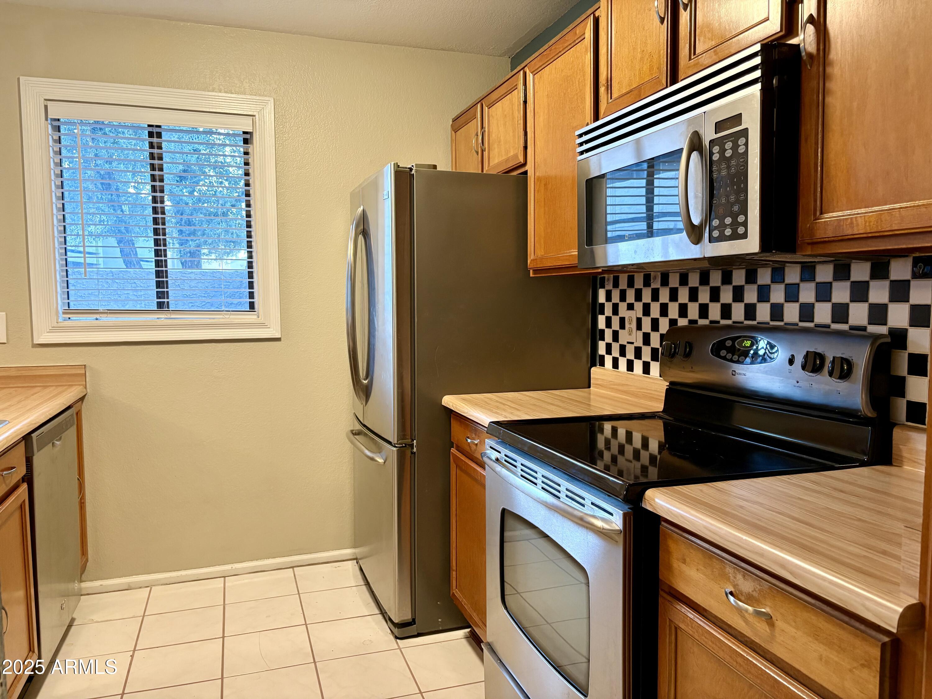 533 West Guadalupe Road, Unit 1122 Mesa, AZ 85210 - Photo 9 of 24 a kitchen with stainless steel appliances granite countertop a refrigerator and a stove