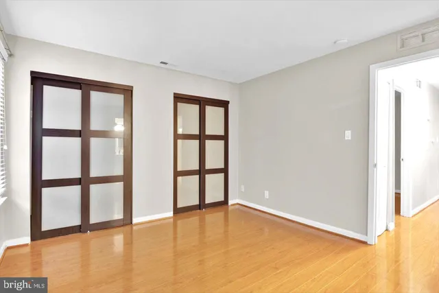 a view of empty room with wooden floor and fan