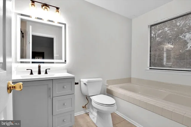 a bathroom with a toilet a sink a mirror a window and vanity