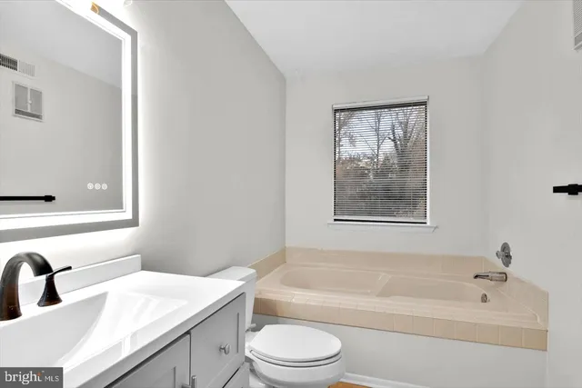 a bathroom with a granite countertop toilet a sink and a bathtub