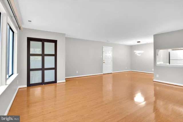 a view of an empty room with window and wooden floor