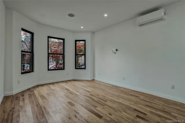 a view of an empty room with window and wooden floor
