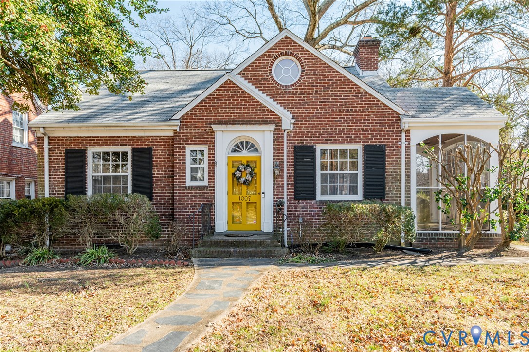 View of front of home featuring a chimney, brick s