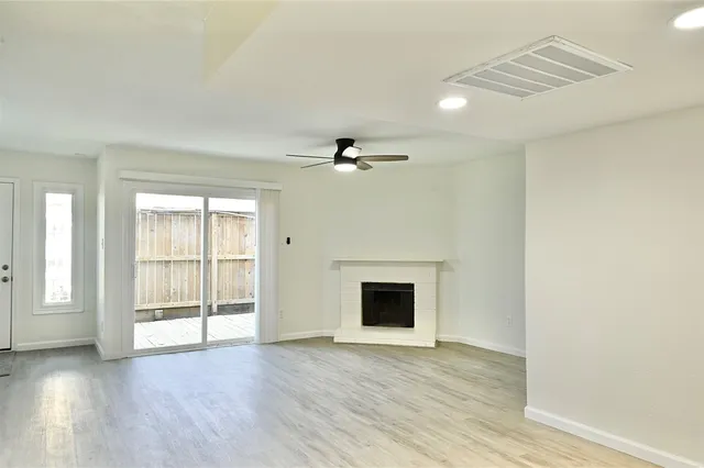 a view of an empty room with wooden floor and a fireplace