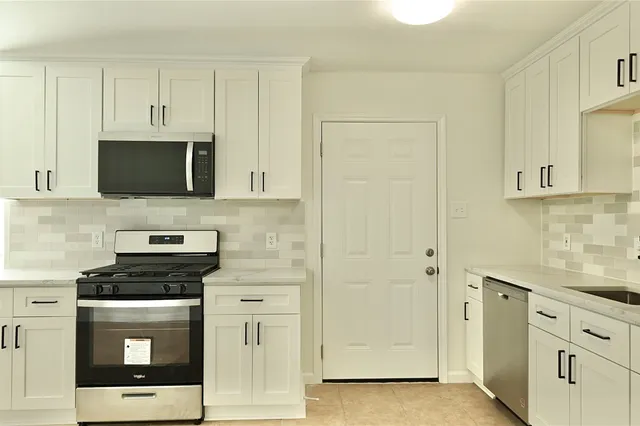 a kitchen with stainless steel appliances white cabinets and a stove top oven