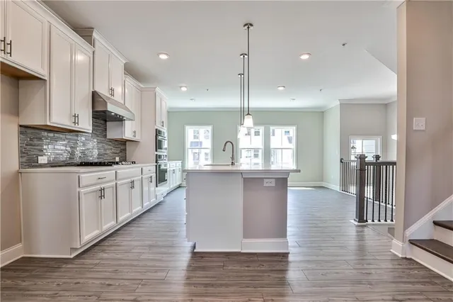 a large kitchen with stainless steel appliances kitchen island a large counter top and a wooden floors