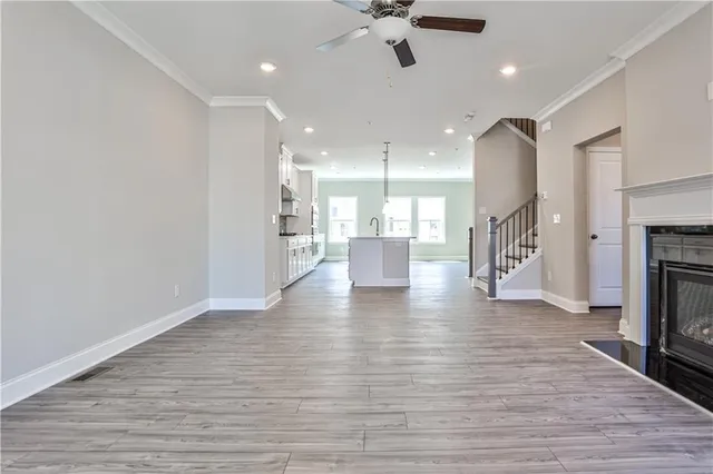 a view of an empty room and a kitchen with a fireplace wooden floor