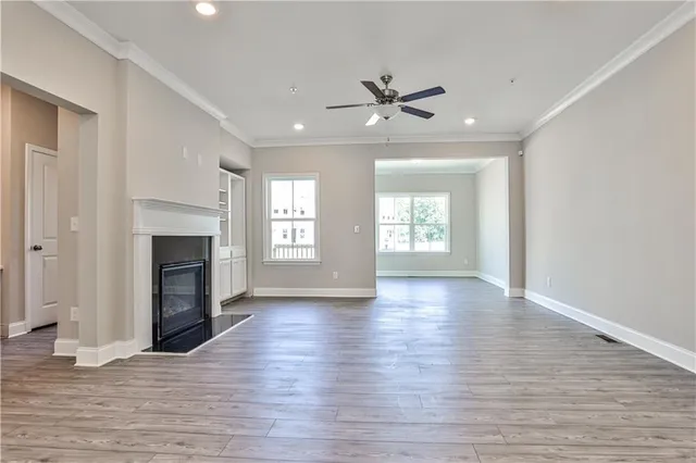 an empty room with wooden floor fireplace and windows
