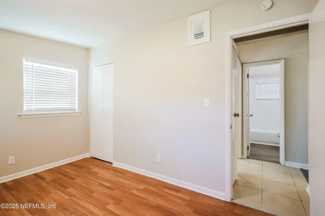 a view of an empty room with closet and a window