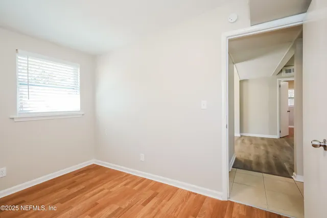an empty room with wooden floor and mirror