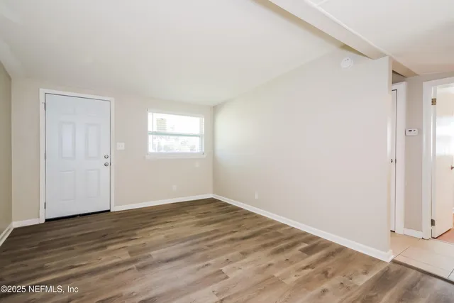 an empty room with wooden floor and window