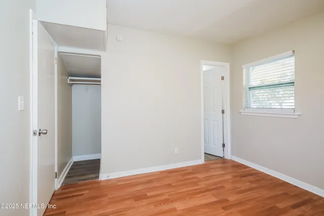 a view of an empty room with wooden floor and a window