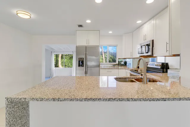 a kitchen with stainless steel appliances granite countertop a sink refrigerator and cabinets