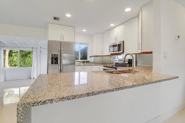 a kitchen with stainless steel appliances granite countertop a sink refrigerator and microwave