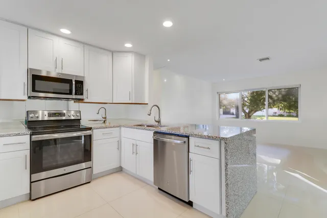 a kitchen with stainless steel appliances granite countertop a stove a sink and a microwave