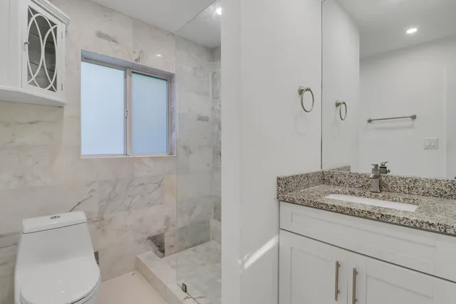 a bathroom with a granite countertop sink toilet and mirror