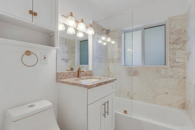 a bathroom with a sink a toilet a mirror a vanity and bathtub