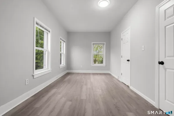 an empty room with wooden floor and windows