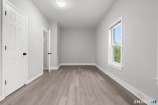 a view of an empty room with wooden floor and a window