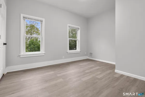 an empty room with wooden floor and windows