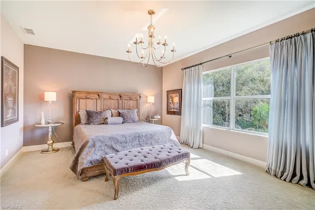 a spacious bedroom with a large bed and a chandelier next to a window