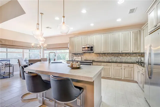 a kitchen with stainless steel appliances granite countertop a stove a refrigerator a sink a dining table and chairs with wooden floor