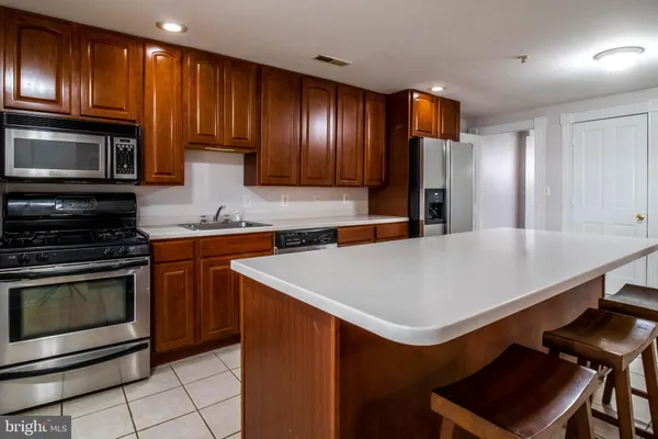 a kitchen with stainless steel appliances wooden cabinets a stove top oven a sink and dishwasher