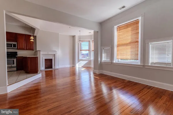 a view of an empty room with window and wooden floor