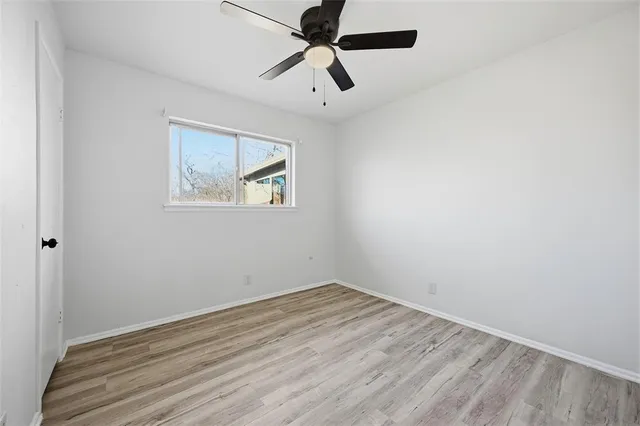 an empty room with a window and a ceiling fan