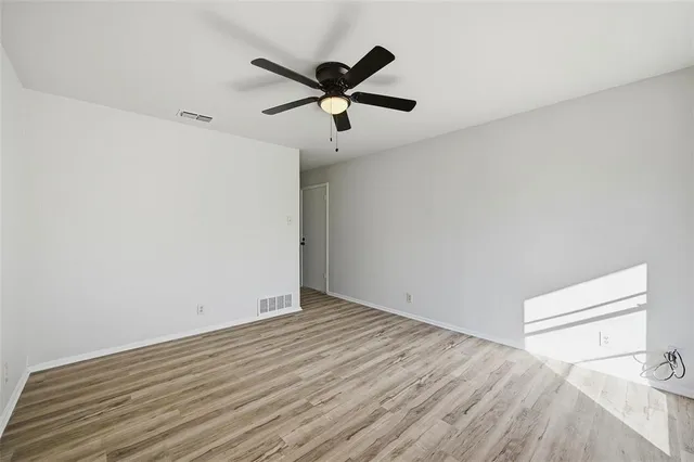 a view of empty room with wooden floor and ceiling fan