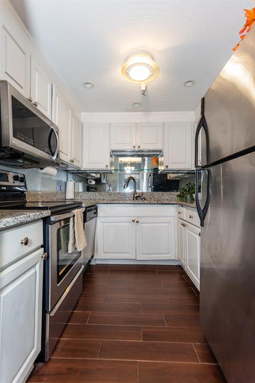 375 Ralph McGill Boulevard Northeast, Unit 1701 Atlanta, GA 30312 - Photo 8 of 33 a kitchen with stainless steel appliances white cabinets a sink a stove a microwave and wooden floors
