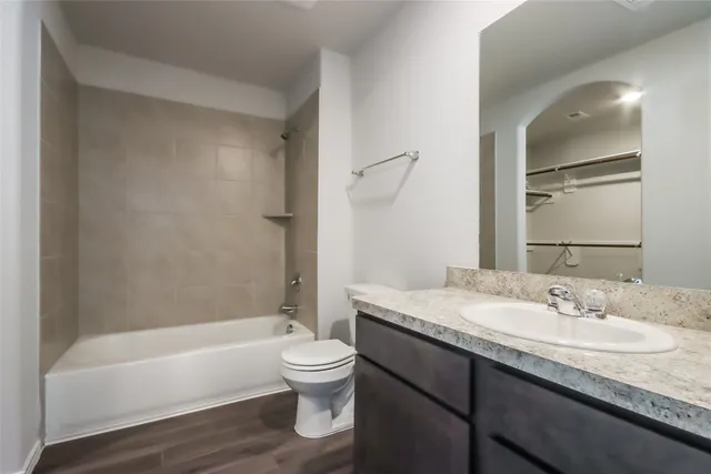 a bathroom with a granite countertop sink a toilet and bathtub