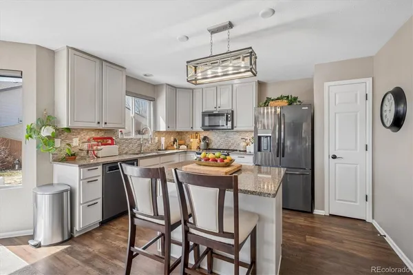a kitchen with stainless steel appliances a dining table chairs and refrigerator