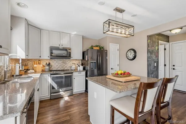 a kitchen with stainless steel appliances granite countertop a stove a sink dishwasher a dining table and chairs with wooden floor