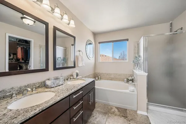 a bathroom with a granite countertop tub sink and mirror