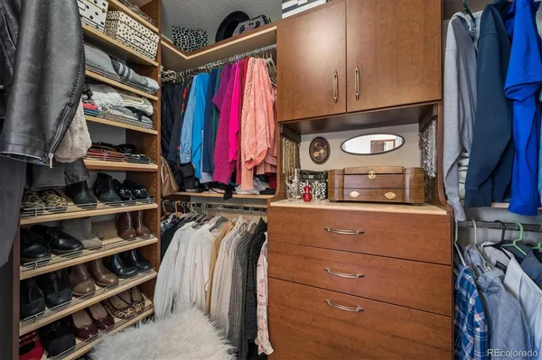 a view of walk in closet with clothes and shoes