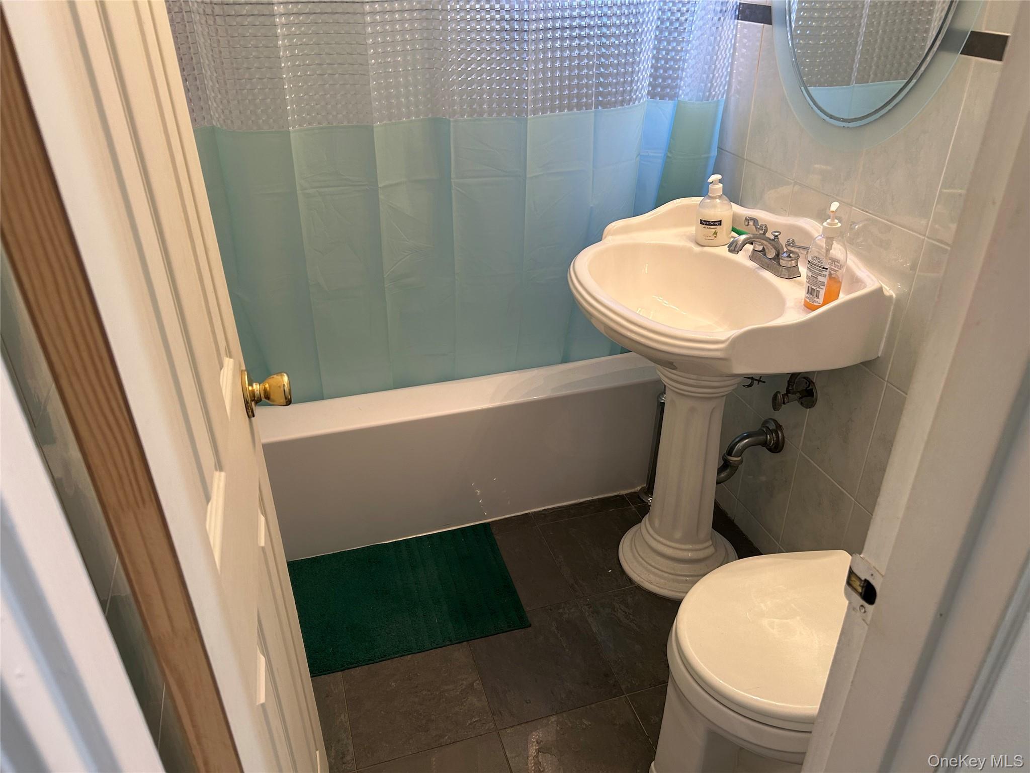 83-20 98th Street, Unit 5J Queens, NY 11421 - Photo 17 of 17 a bathroom with a sink a toilet a mirror and shower curtain