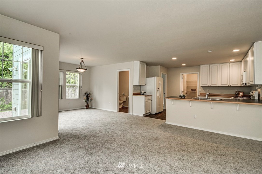 2402 Southeast 2nd Place Renton, WA 98056 - Photo 13 of 40 a large open kitchen with a refrigerator a stove top oven and white cabinets