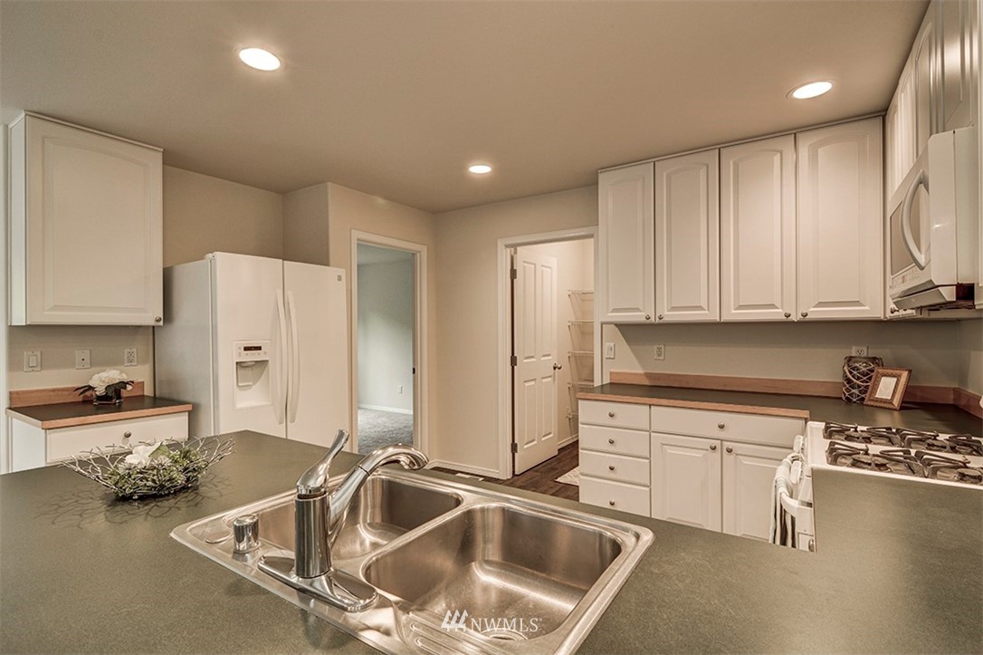 2402 Southeast 2nd Place Renton, WA 98056 - Photo 5 of 40 a kitchen with stainless steel appliances granite countertop a sink a stove and a refrigerator with wooden floor