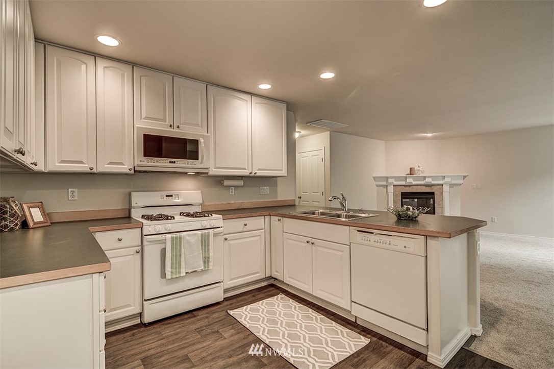 2402 Southeast 2nd Place Renton, WA 98056 - Photo 6 of 40 a kitchen with stainless steel appliances granite countertop a stove top oven a sink and white cabinets