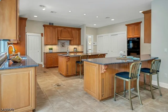 a kitchen with stainless steel appliances granite countertop a stove top oven a sink a dining table and chairs