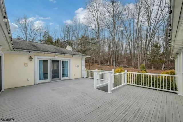 a view of a white house with a large window and wooden fence
