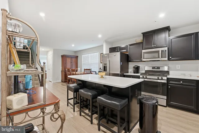 a kitchen with stainless steel appliances granite countertop a stove top oven a refrigerator a sink and chairs