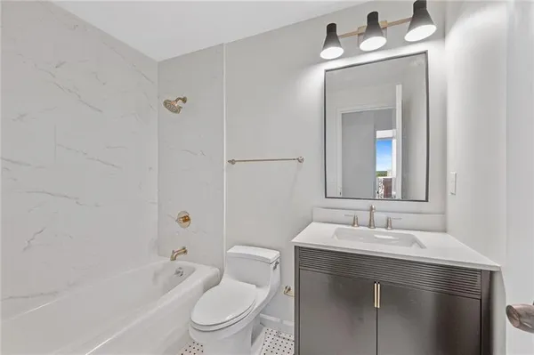a bathroom with a toilet a sink a mirror a bathtub and vanity